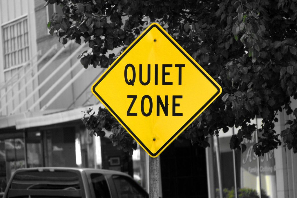 Black and white background with yellow road sign reading 'Quiet Zone' for Autism Hour